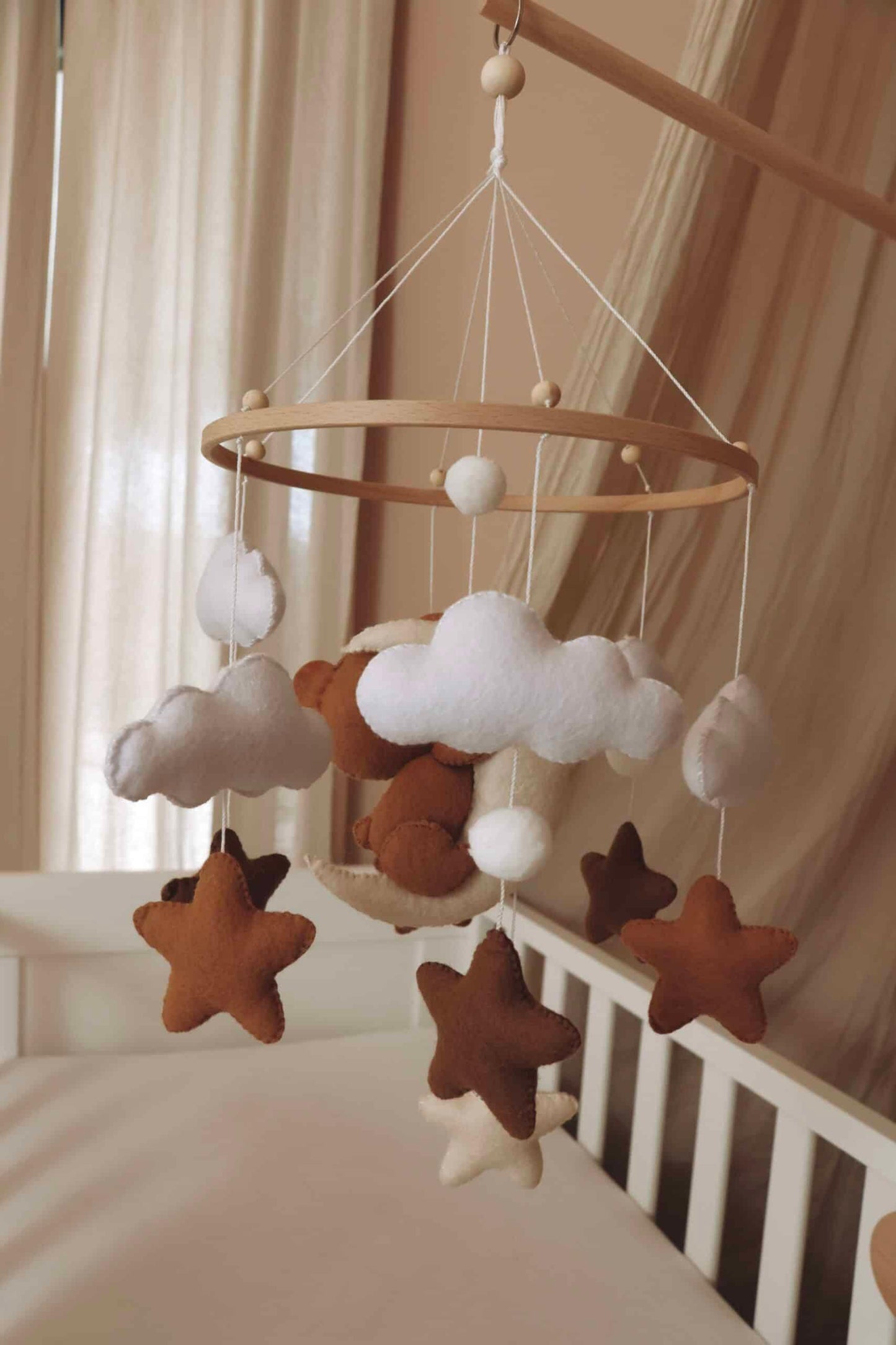 Mobile bébé en feutrine avec étoiles, nuages et ours suspendus au-dessus d’un lit enfant