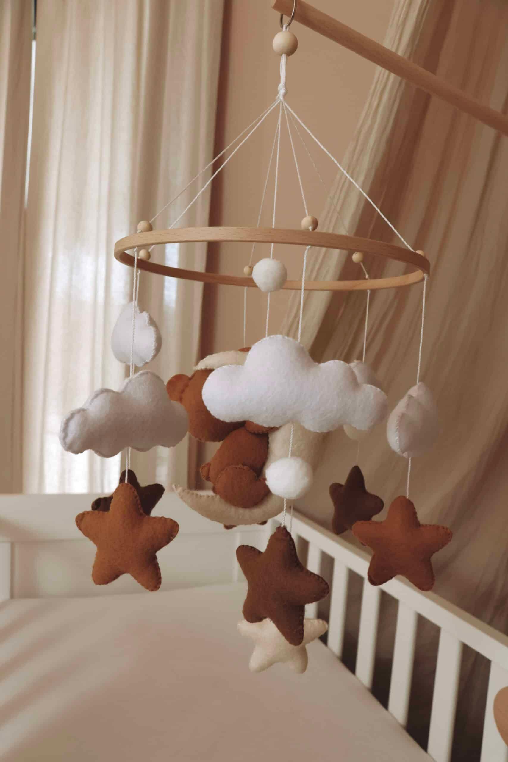 Mobile bébé en feutrine avec étoiles, nuages et ours suspendus au-dessus d’un lit enfant
