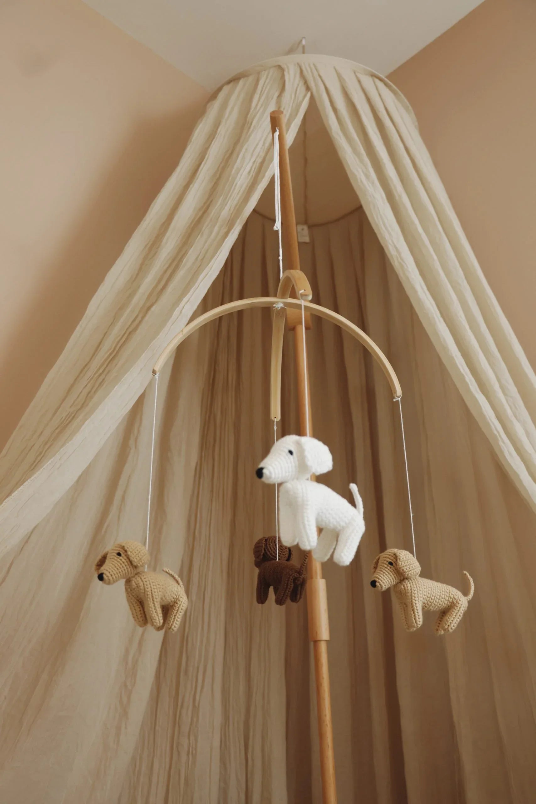 Mobile bébé en bois avec chiens tricotés suspendus, décoration chambre enfant beige.