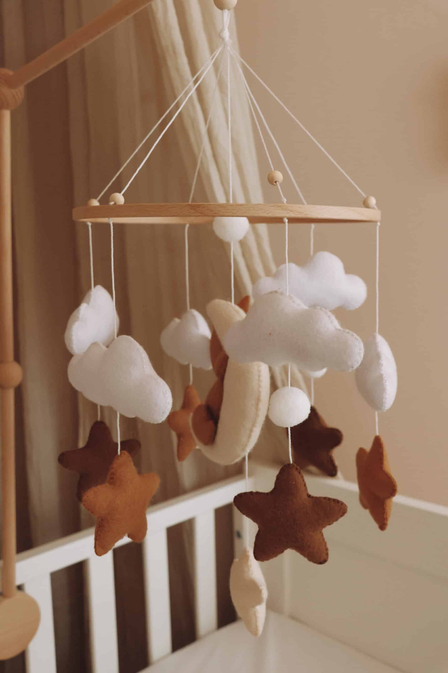 Mobile bébé en feutrine nuages et étoiles suspendu au-dessus d’un lit enfant