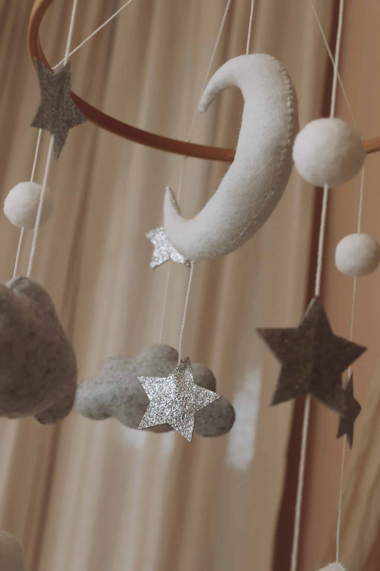 Mobile bébé en feutrine avec lune, étoiles argentées et nuages décoratifs suspendus.