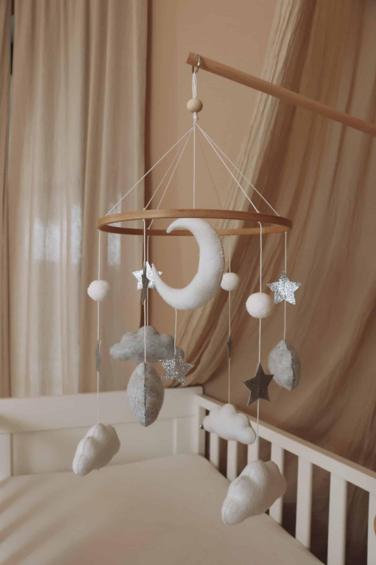 Mobile bébé en feutre, nuages, lune et étoiles, suspendu au-dessus d’un lit enfant