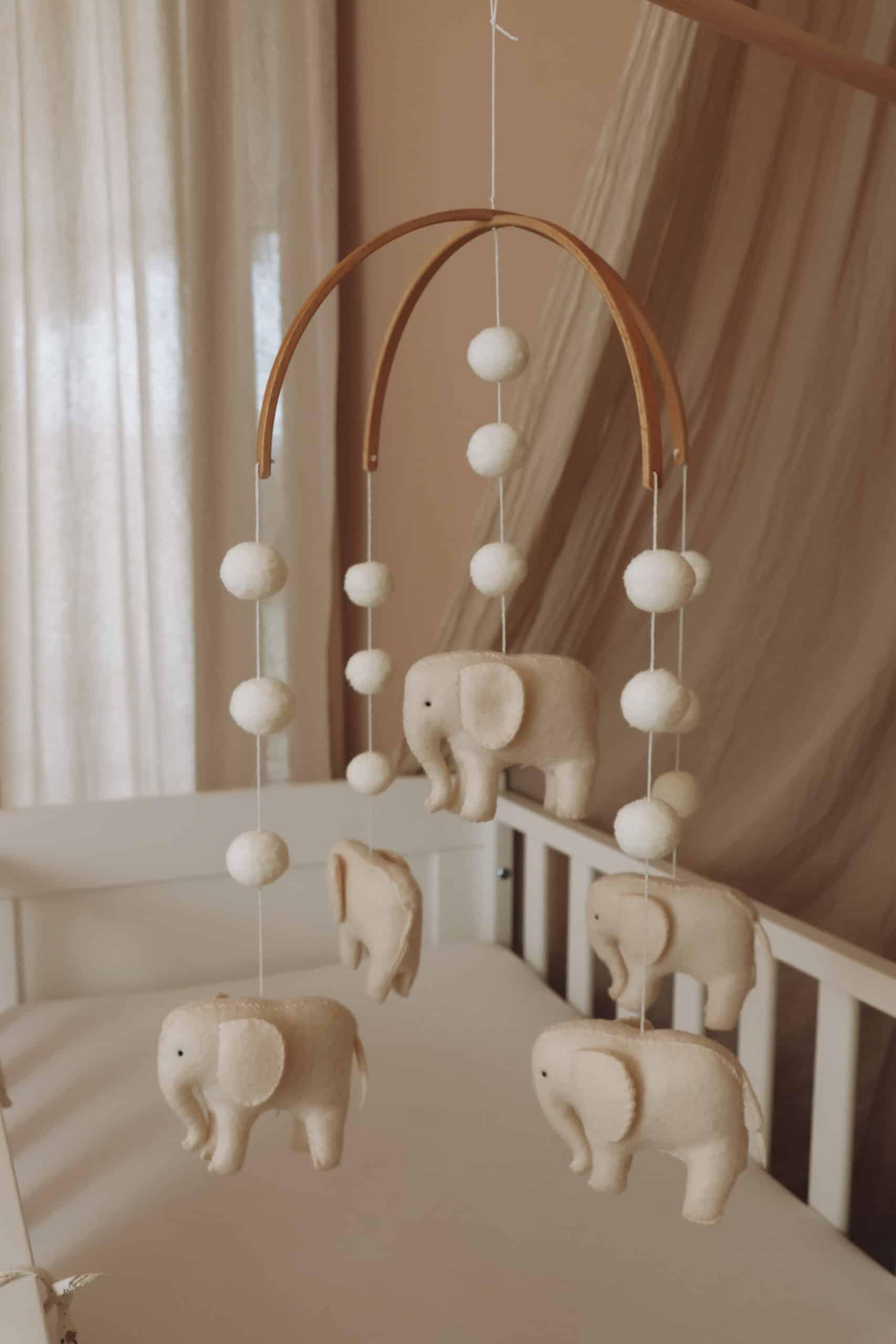 Mobile bébé en feutrine avec éléphants et boules décoratives suspendu au-dessus d’un berceau