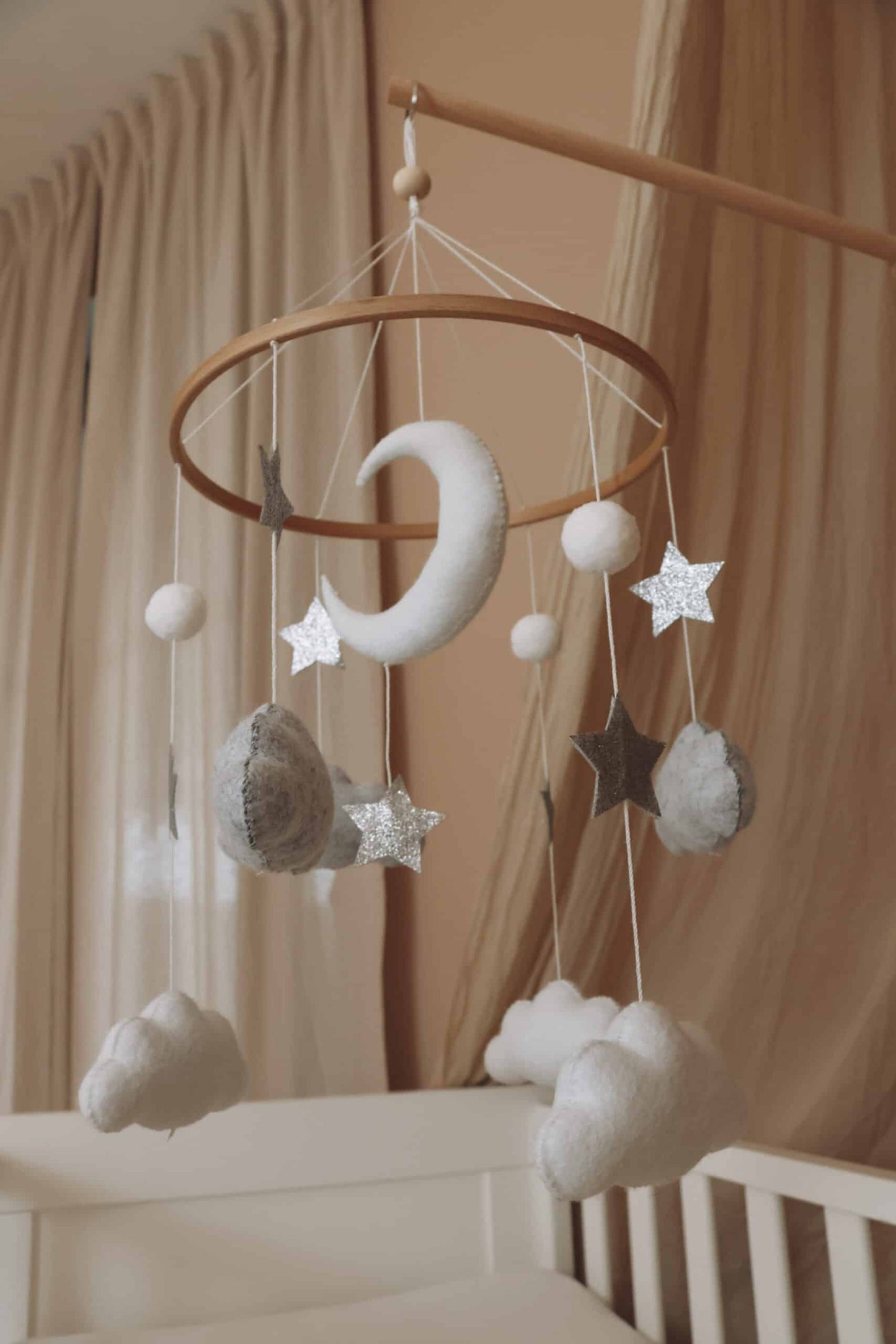 Mobile bébé en feutre avec lune, étoiles et nuages suspendus dans une chambre enfant