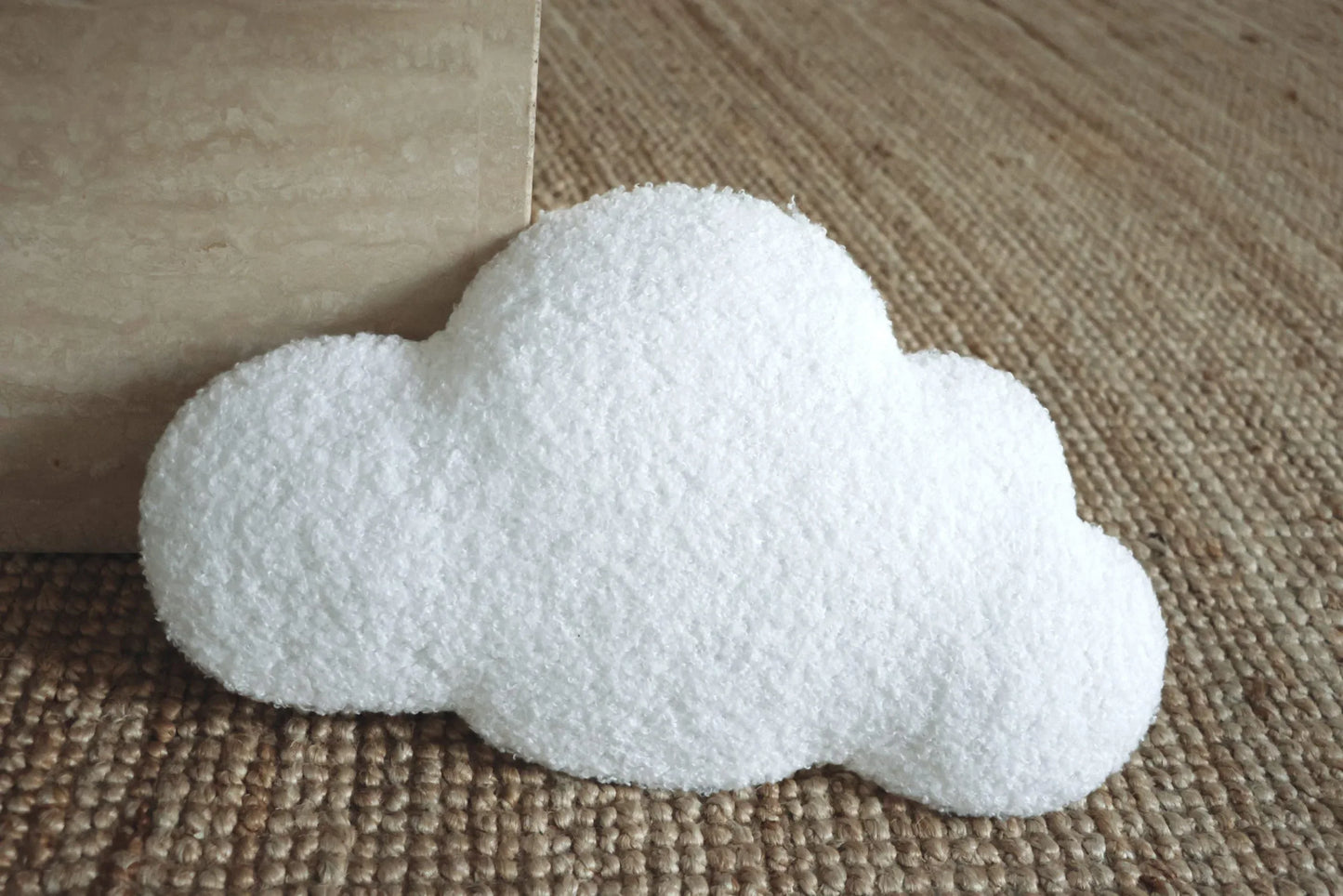 Coussin nuage blanc texturé pour décoration chambre enfant, posé sur tapis en jute